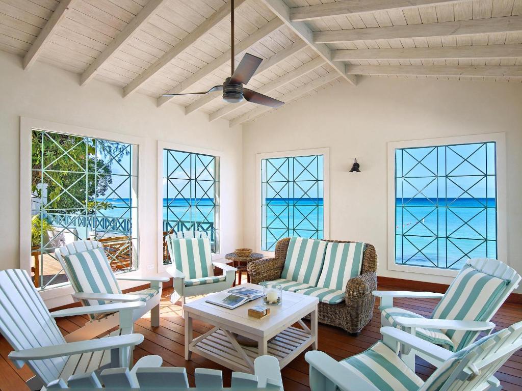 a living room with chairs and a table and windows at Southwinds Beach House in Saint Peter