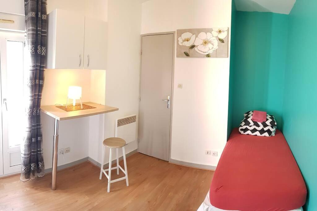 a room with a desk and a table and a stool at Studio de 12m² agréable calme proche CHU in Dijon