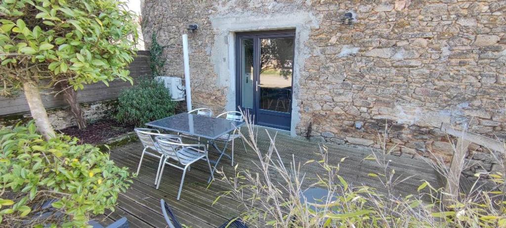 una mesa y sillas en una terraza de madera junto a un edificio en Gîte à la campagne en Saint-Brice-sur-Vienne