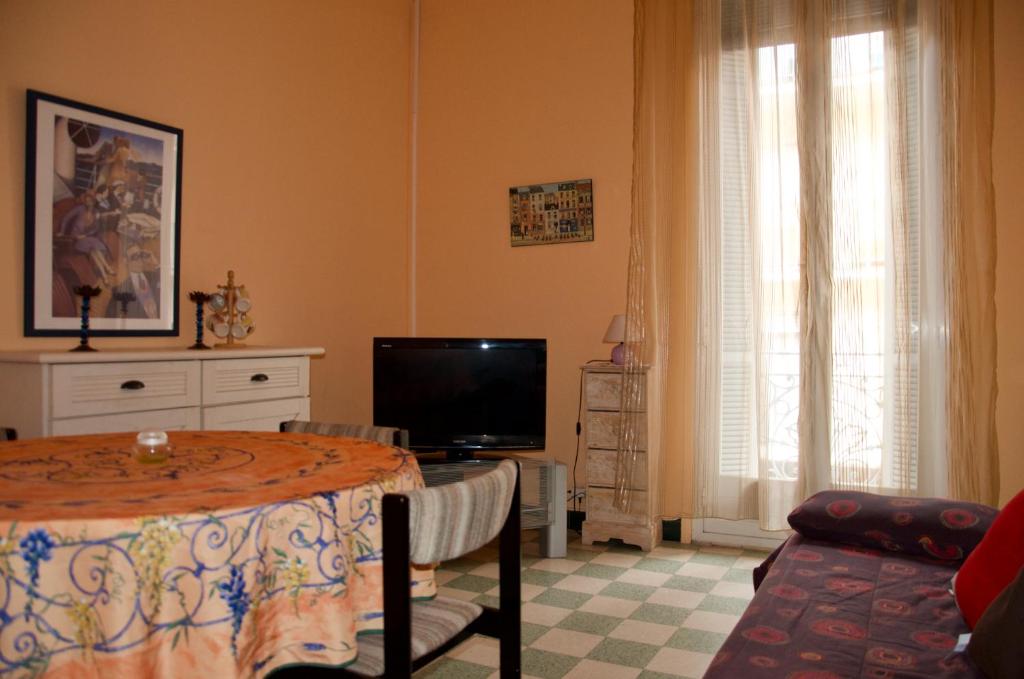 ein Wohnzimmer mit einem Tisch und einem TV in der Unterkunft Appartement 2 Les Clématites in Menton