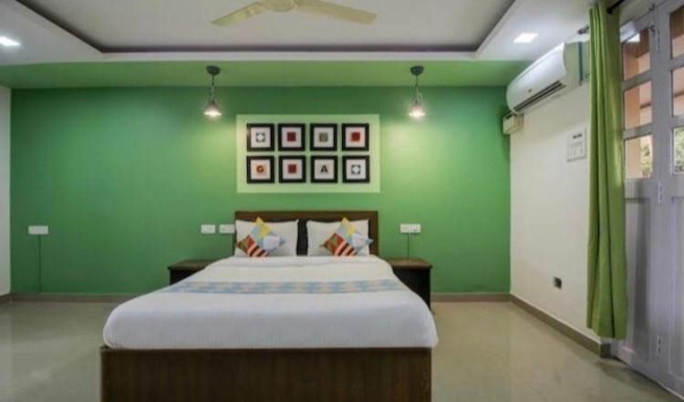 a bedroom with a large bed with green walls at Hotel Sai Advika in Mapusa