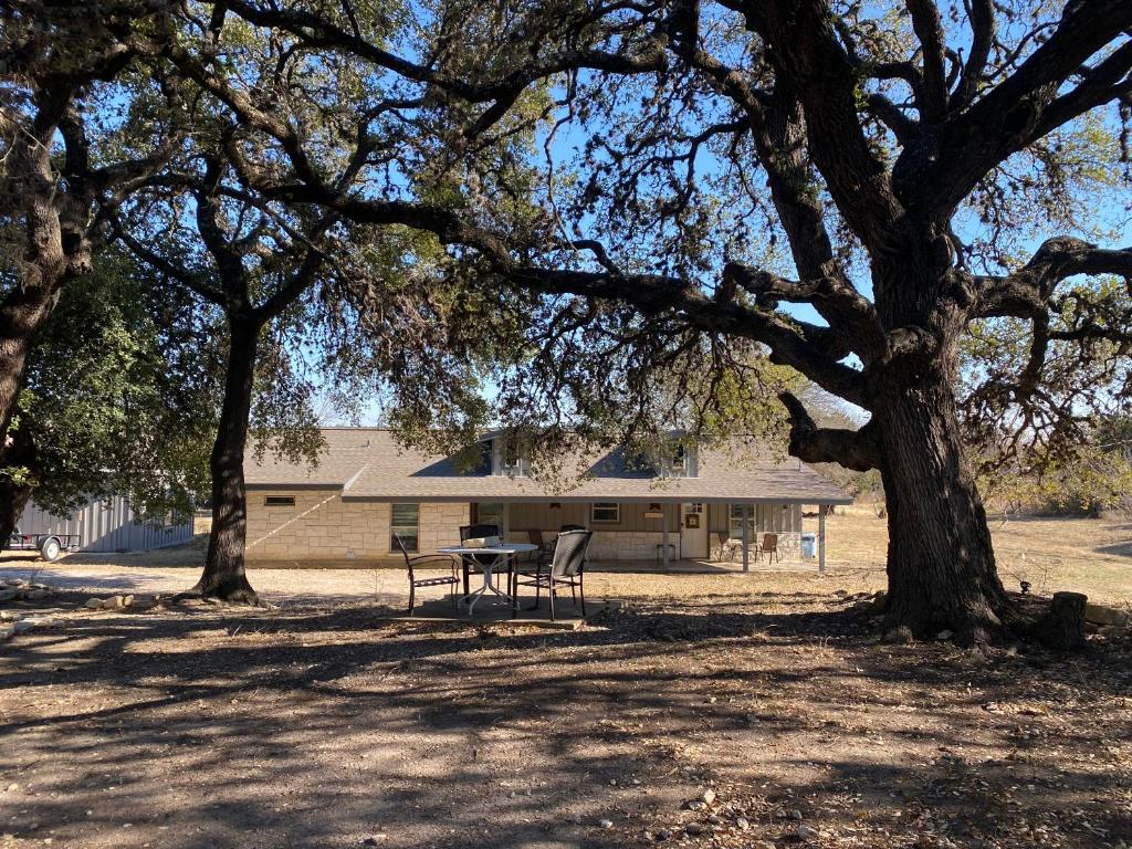 una mesa de picnic y dos sillas bajo un árbol en Texas Hill Country Ranch House - Great Views - Near Hidden Falls Park, en Smithwick
