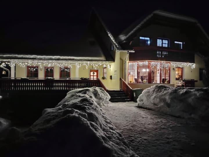 une maison avec des lumières de Noël dans la neige dans l'établissement Apartmaji Boštjan Pristavec, à Kranjska Gora