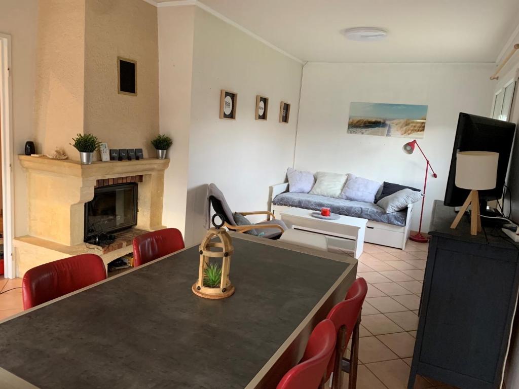 een woonkamer met een tafel en een bank bij Maison chaleureuse avec cheminée et extérieur in Luxeuil-les-Bains