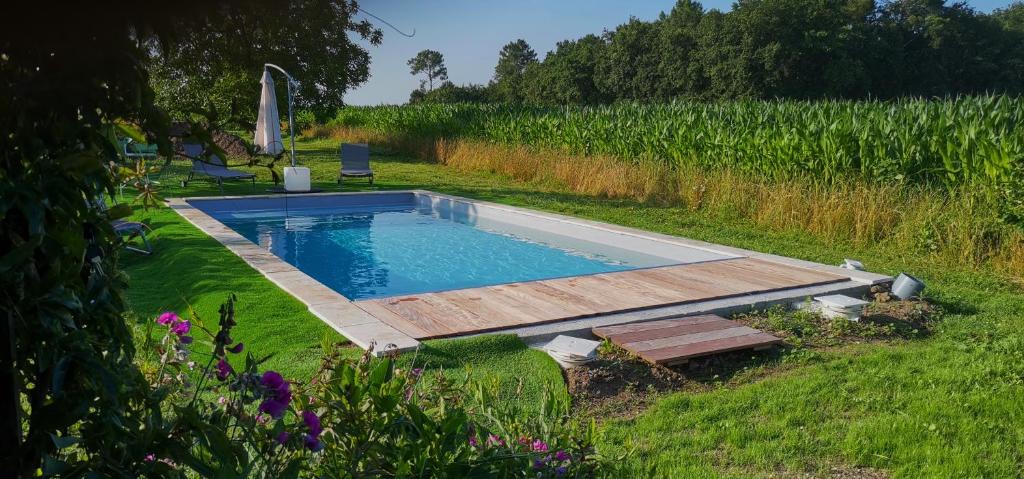 a swimming pool with a wooden deck in a field at LES LIMORNIERES in Le Grand-Pressigny