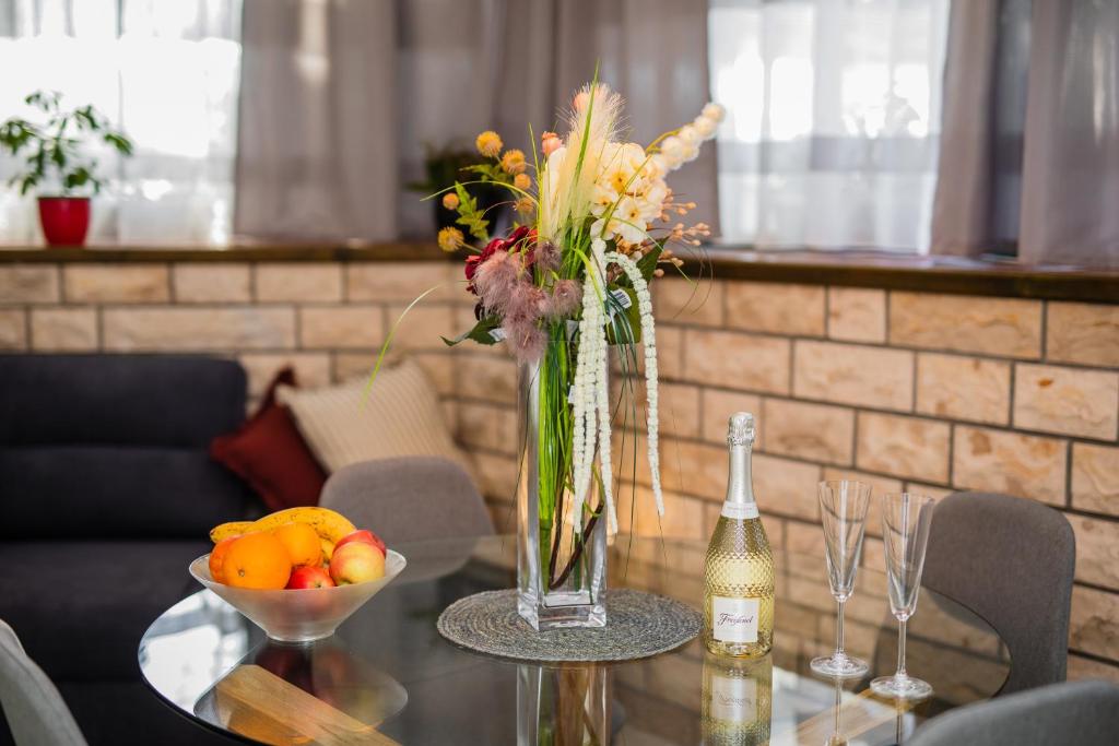 a table with a vase of flowers and a bowl of fruit at Glicinia in Šibenik