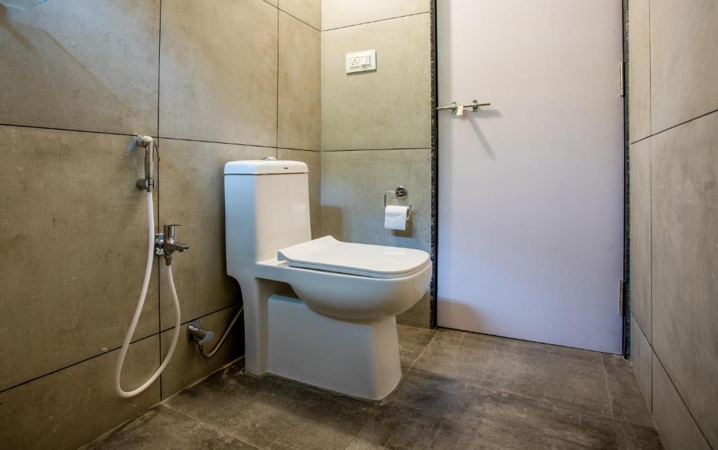 a bathroom with a toilet and a shower stall at Whiteboard Homes Siolim in Siolim