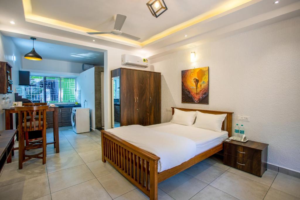 a bedroom with a large bed and a kitchen at Whiteboard Homes Siolim in Siolim