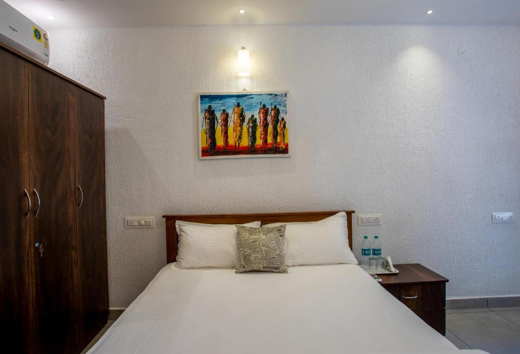 a bedroom with a white bed with a picture on the wall at Whiteboard Homes Siolim in Siolim