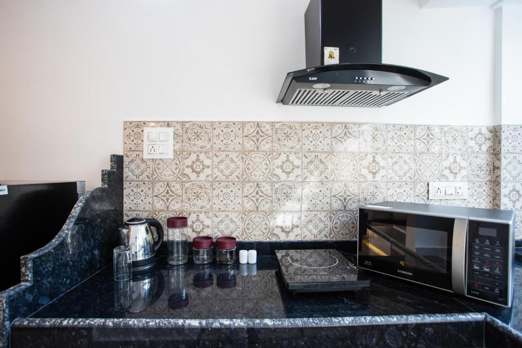 a kitchen with a black counter top with a microwave at Whiteboard Homes Siolim in Siolim