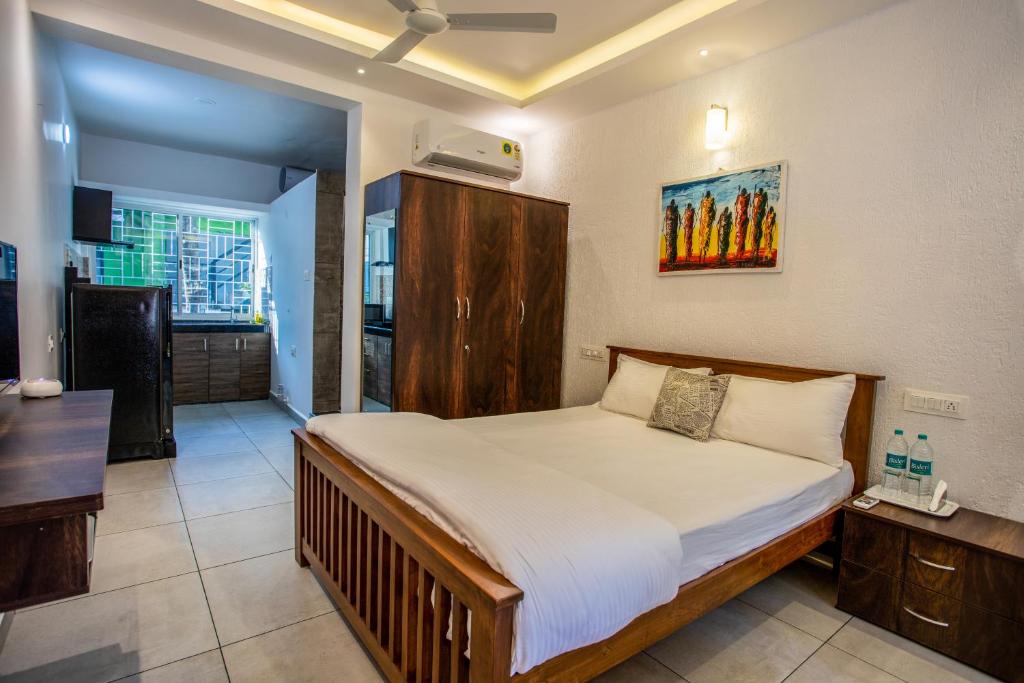 a bedroom with a bed and a kitchen at Whiteboard Homes Siolim in Siolim