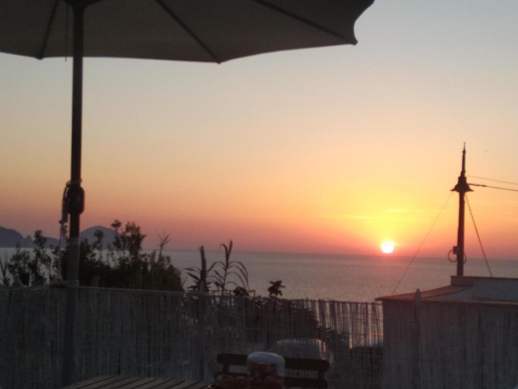 einen Sonnenuntergang über dem Meer mit einem Regenschirm in der Unterkunft Ponzamania Casa Silvana Ponza in Ponza
