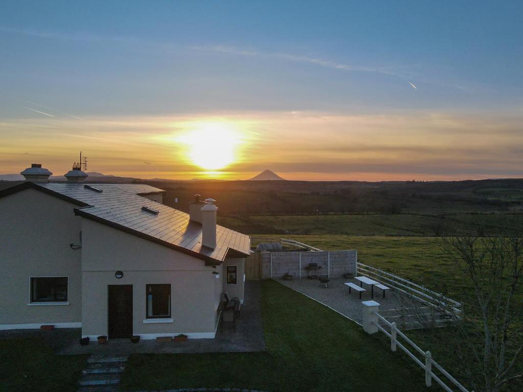 a white house with the sunset in the background at Helens Self Catering in Castlebar
