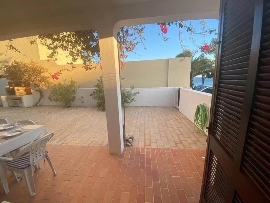 Une porte ouverte s'ouvre sur une terrasse avec une table et des chaises. dans l'établissement T2 sobre a praia - Albufeira/Olhos de Água, à Albufeira