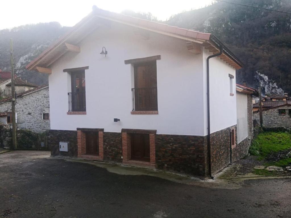 une maison blanche avec deux fenêtres et une allée. dans l'établissement Casa Rural Güilones, Parque Natural de Ponga, à Sobrefoz