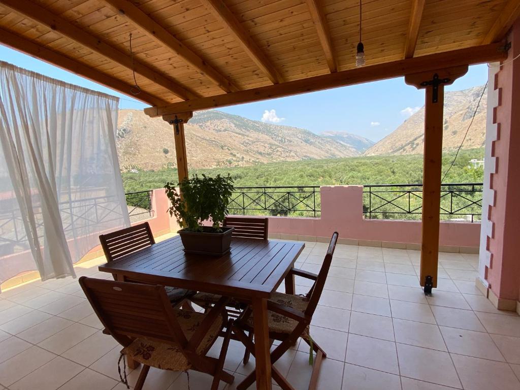 einen Holztisch und Stühle auf einer Terrasse mit Bergen im Hintergrund in der Unterkunft Gkiko’s Guest House in Qeparo