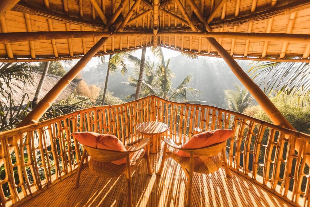 une terrasse en bois avec des chaises et une table. dans l'établissement Ananda House 3bds Eco Bamboo House Pool River View, à Bringkit