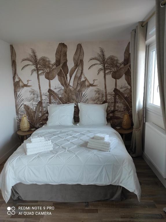 - une chambre avec un lit orné d'une fresque murale de palmiers dans l'établissement Appartement de charme, à Courseulles-sur-Mer