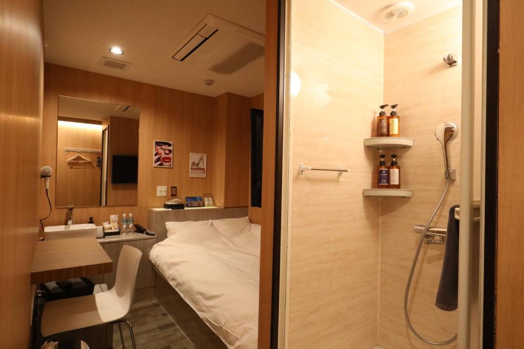 a bathroom with a shower and a bed and a sink at Hotel Charire Kichijoji in Kichijōji