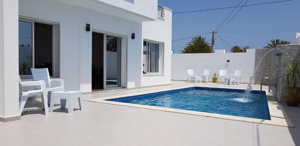 a white house with a swimming pool in a yard at Villa Aline Lagune Djerba in Midoun