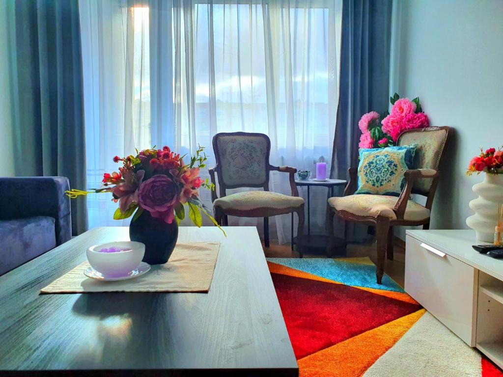 a living room with a table with a vase of flowers at Lovely 2-bedroom Flat in Šiauliai in Šiauliai