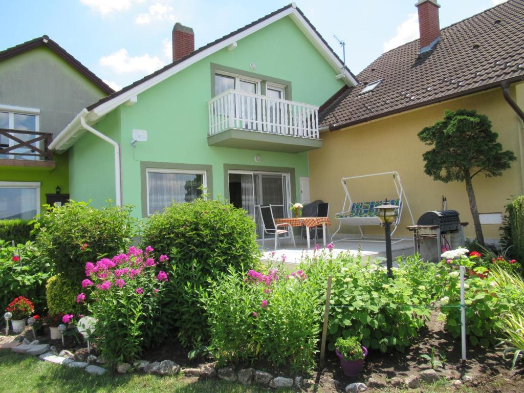 a house with a balcony and flowers in the yard at Vízközeli nyaralo 6 fo reszere Velencen VCE-7 in Buhinpuszta