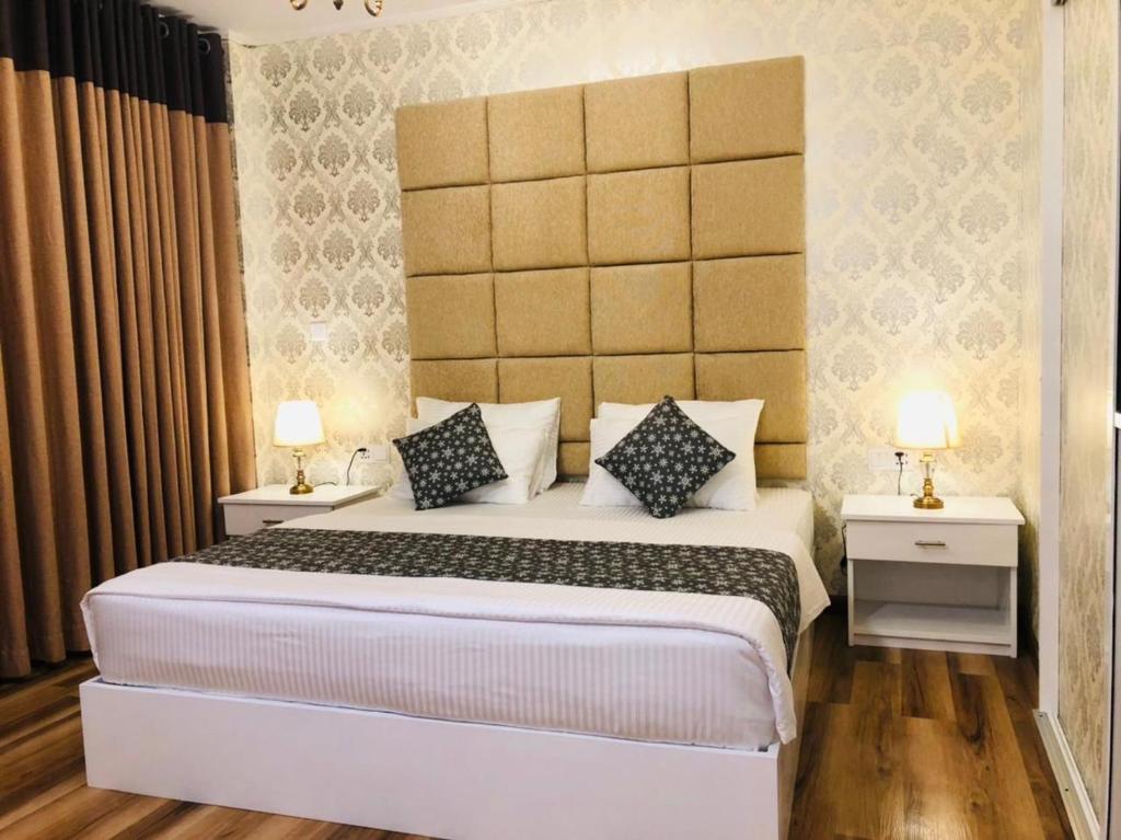 - une chambre dotée d'un grand lit blanc avec deux tables et deux lampes dans l'établissement Hotel Bonavista, à Nuwara Eliya