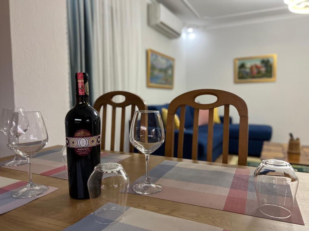 a bottle of wine sitting on a table with two glasses at Chestnut Yard Villa in Tirana