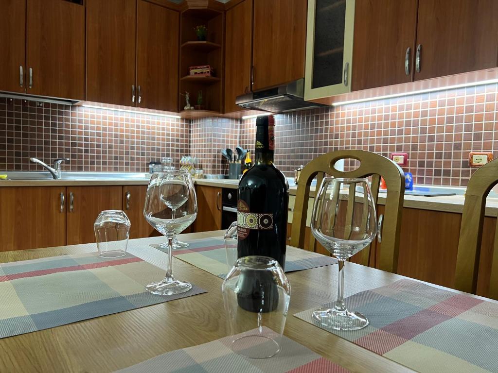 a bottle of wine sitting on a table with two wine glasses at Chestnut Yard Villa in Tirana