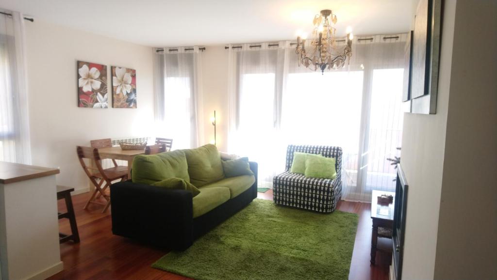 ein Wohnzimmer mit einer grünen Couch und einem Tisch in der Unterkunft Las Margas. Golf. Bici. Esquí. Piscina. in Sabiñánigo