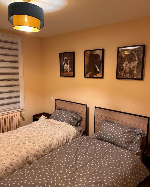 - une chambre avec 2 lits et des photos sur le mur dans l'établissement OLGA Chambre d'hote, à Verdun-sur-Meuse