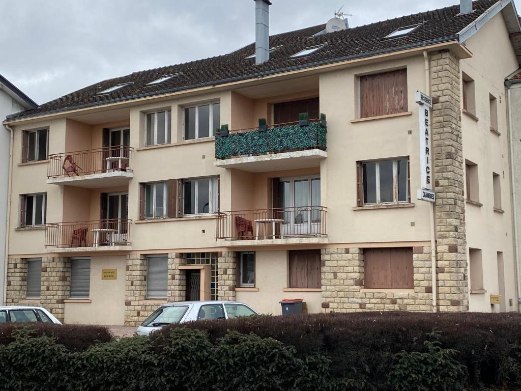 an apartment building with a balcony and cars parked in front at Les studios meublés de la résidence Beatrice in Bourbonne-les-Bains