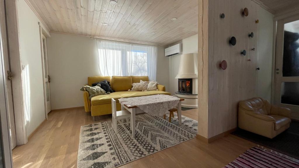 a living room with a yellow couch and a table at Cozy Little House Meex - 5km from Võru in Meegomäe