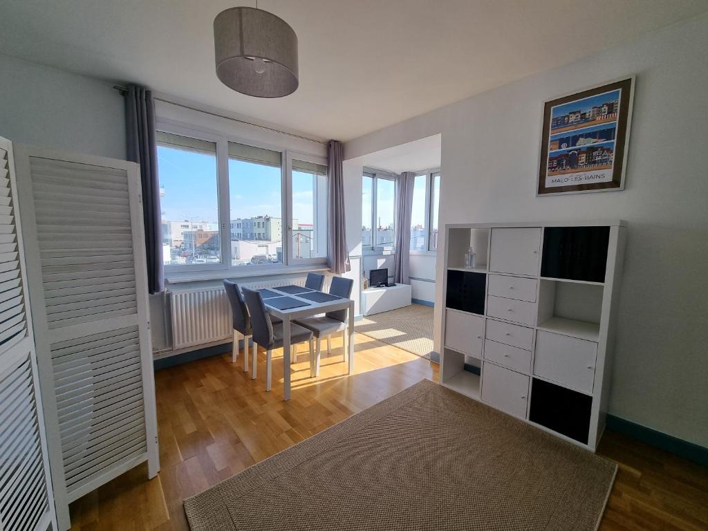 een woonkamer met een bureau en een tafel met een raam bij Studio Malouin - Sur la digue de Malo les Bains avec vue sur mer in Malo-les-Bains