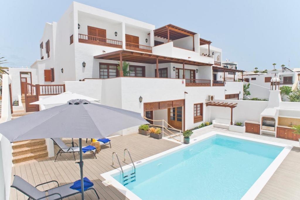 eine Villa mit einem Pool und einem Sonnenschirm in der Unterkunft Villa Pilar in Puerto del Carmen
