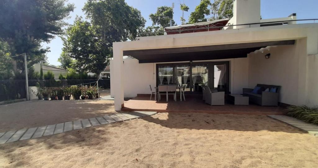 mały biały dom z patio i stołem w obiekcie Casa Punta de Los Ingleses w mieście Punta Umbría