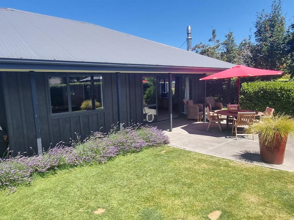 a house with a patio with a table and an umbrella at 7d Coleridge Street in Hanmer Springs