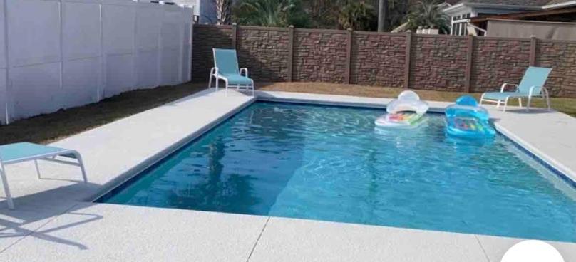 a pool with two chairs and a child in a pool toy at Hidden Beach Oasis in Myrtle Beach