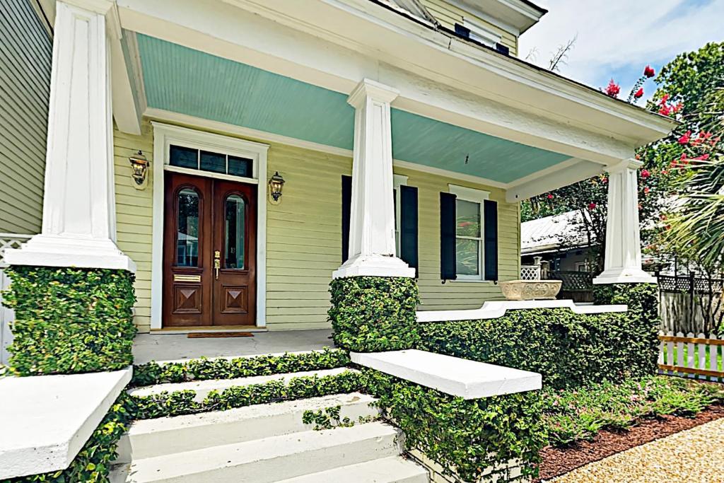a green house with white columns and a door at Anderson Place in Savannah