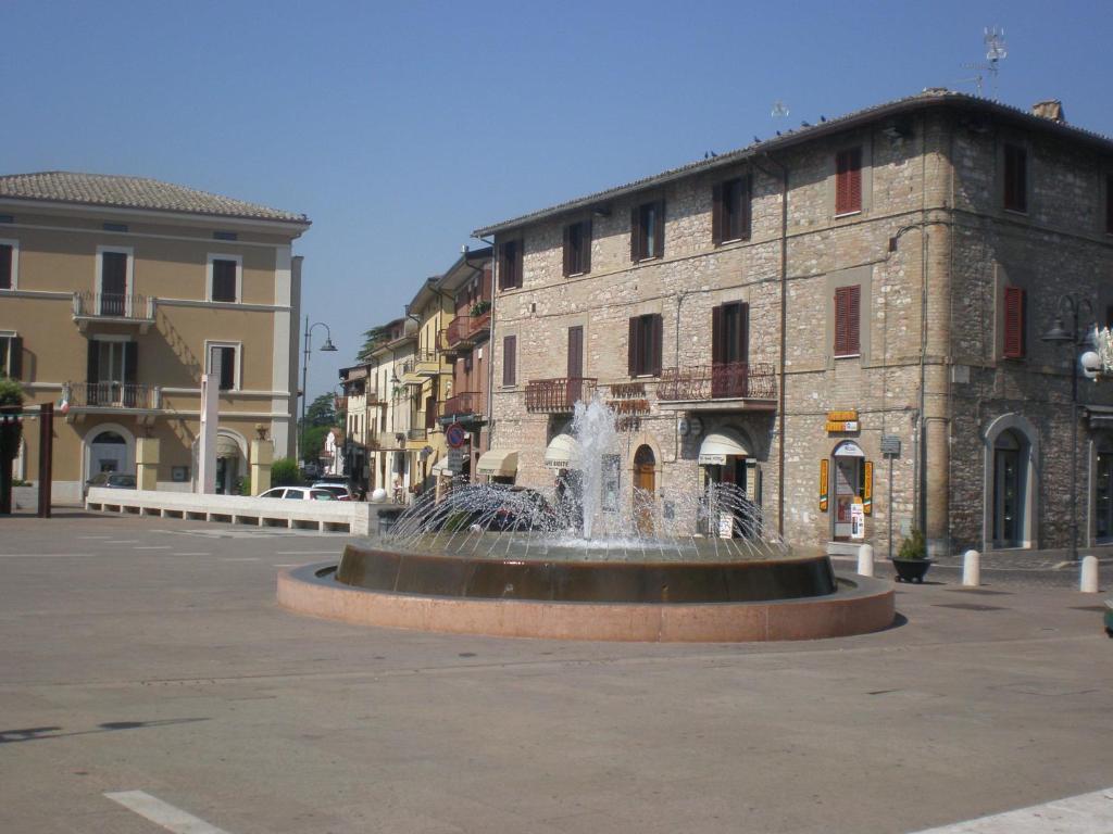 una fontana in mezzo a una strada di fronte a un edificio di Piazza degli Angeli ad Assisi