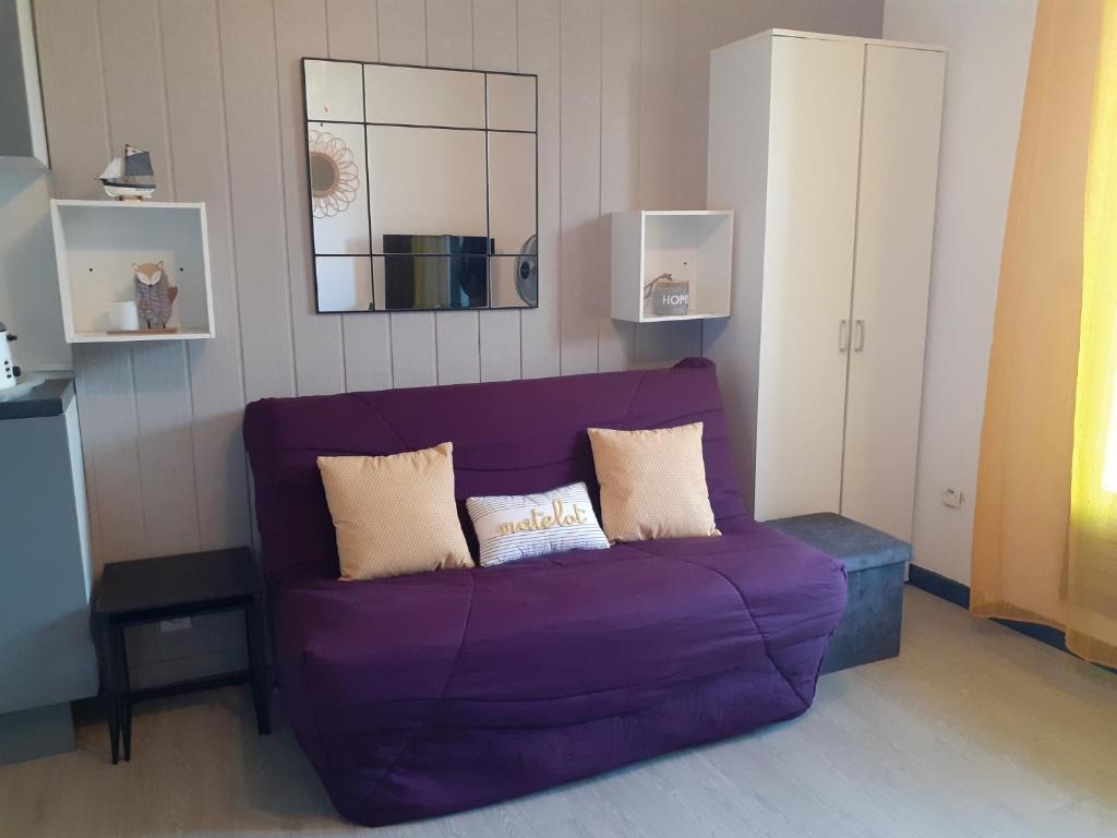 a purple couch in a living room with a mirror at Appartement Canet Sud Jardin et parking in Canet-en-Roussillon