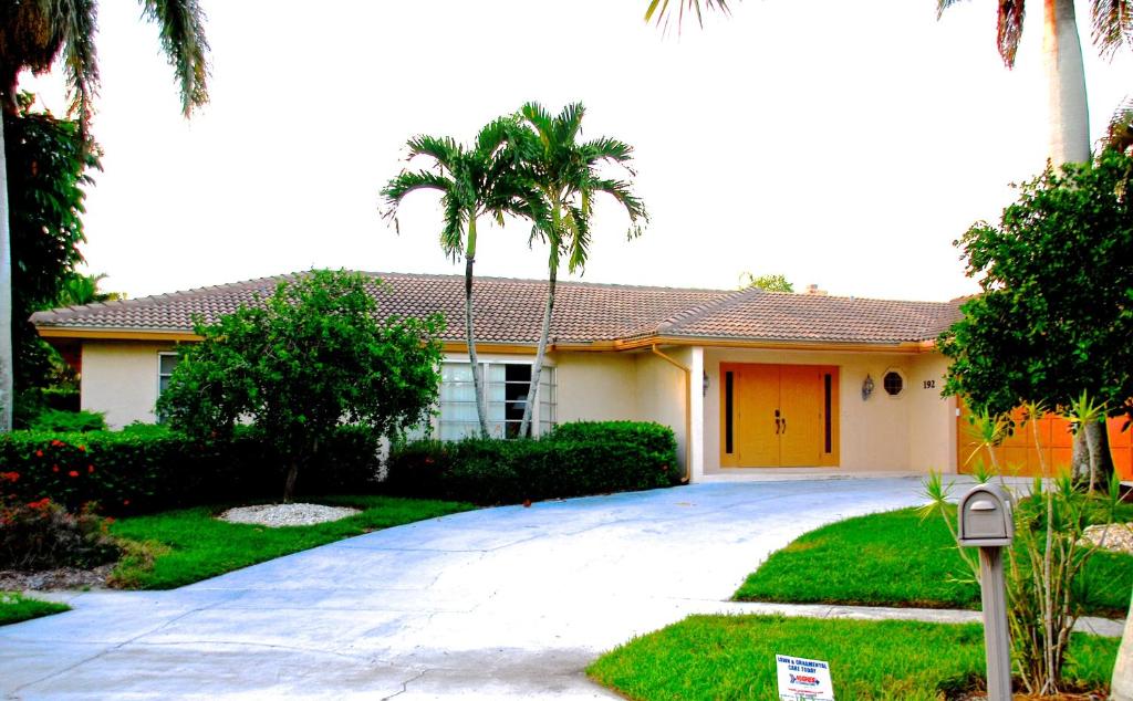 a house with a yellow door and palm trees at Villa Marco Island in Marco Island