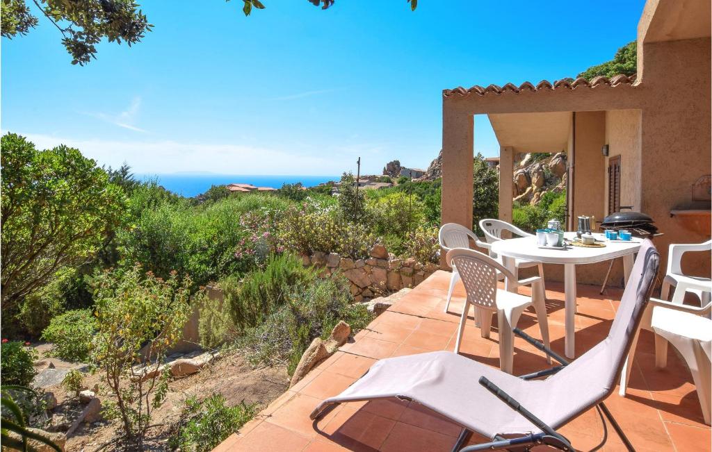 um pátio com uma mesa e cadeiras e o oceano em Nice Home In Trinita Dagultu Vignol With Kitchen em Li Valcaggi