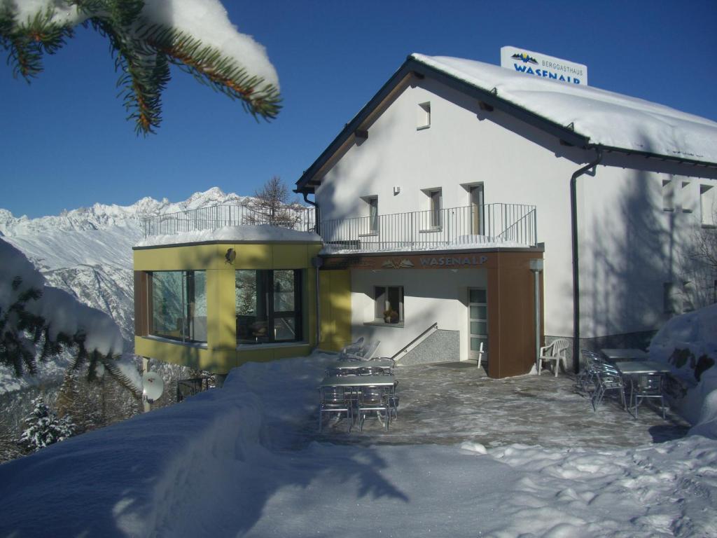 a building with tables and chairs in the snow at Berggasthaus Wasenalp in Brig