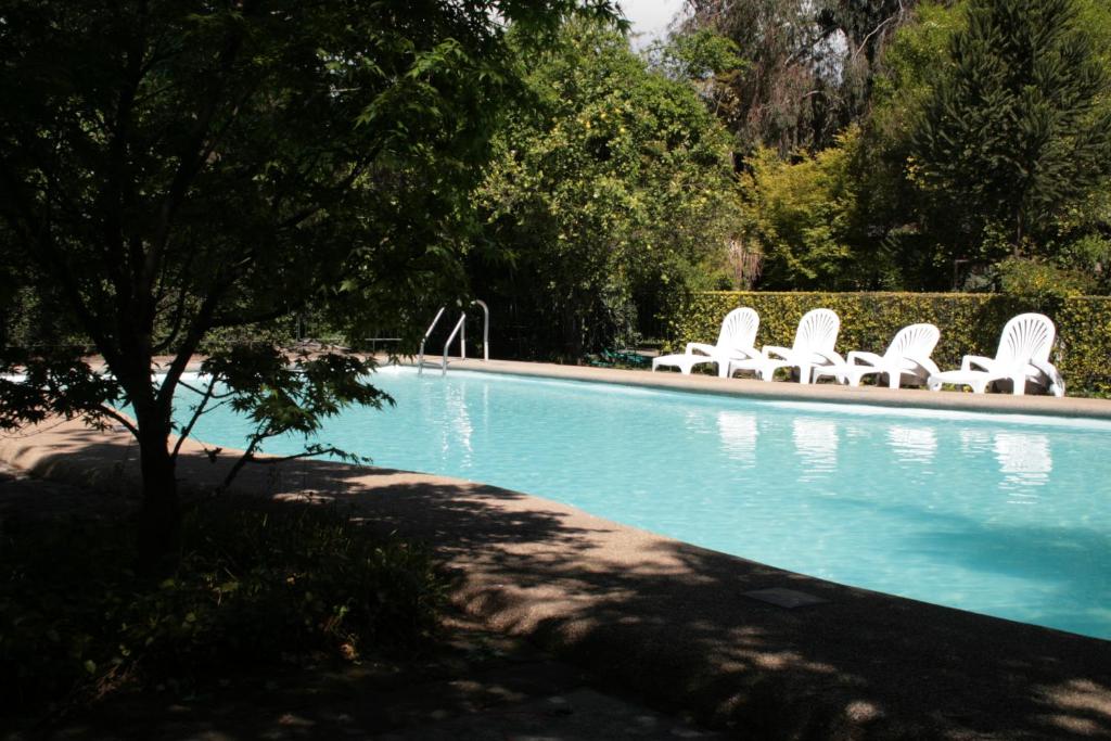 a swimming pool with white lawn chairs next to it at Hotel Acacias de Vitacura in Santiago