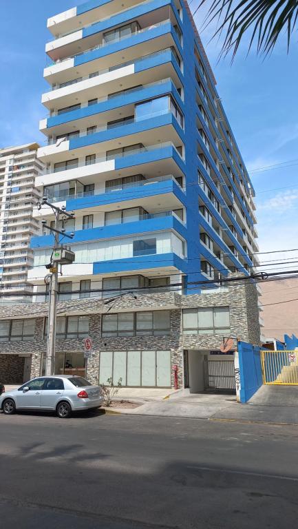 une voiture garée devant un grand bâtiment dans l'établissement DEPARTAMENTO EDIFICIO AZUL I, à Iquique