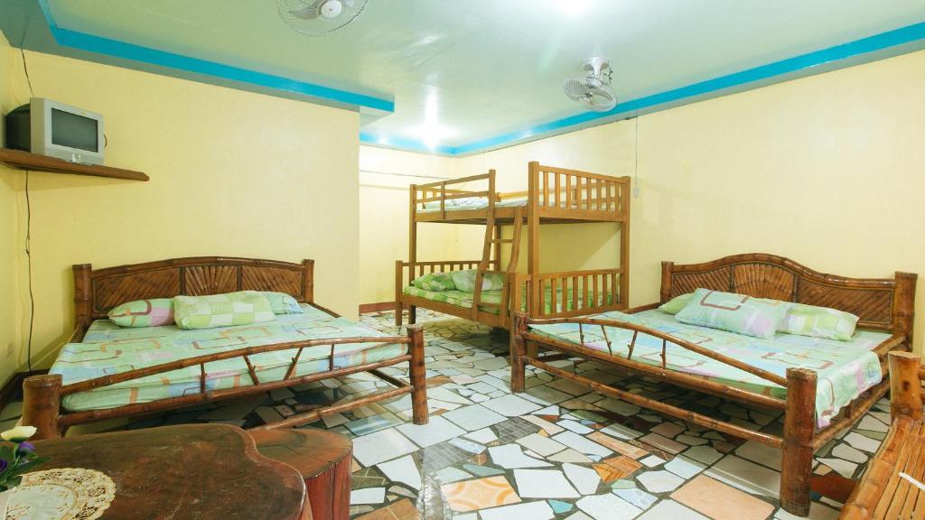 Zimmer mit 2 Etagenbetten und einem TV in der Unterkunft RGV Beach Resort Batangas in Calatagan