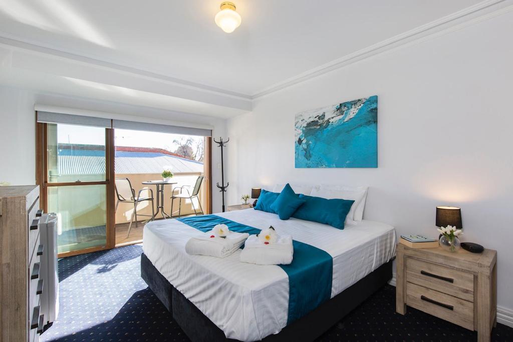 a bedroom with a large bed and a balcony at Charm on Carrington in Adelaide