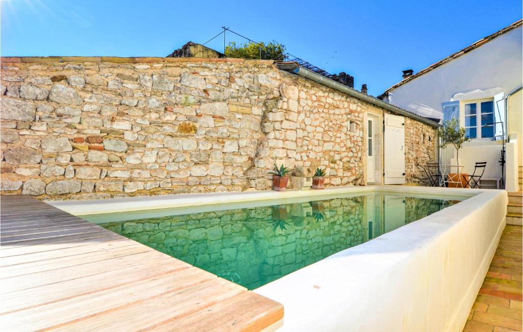 a swimming pool in front of a stone wall at Nice Home In Verfeuil With Wifi, Private Swimming Pool And Outdoor Swimming Pool in Verfeuil