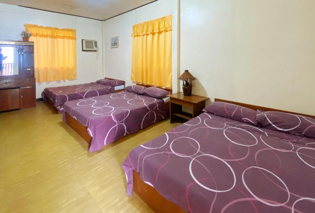 two beds in a room with purple comforters at RedDoorz Hostel @ Molino Beach Resort in Zambales